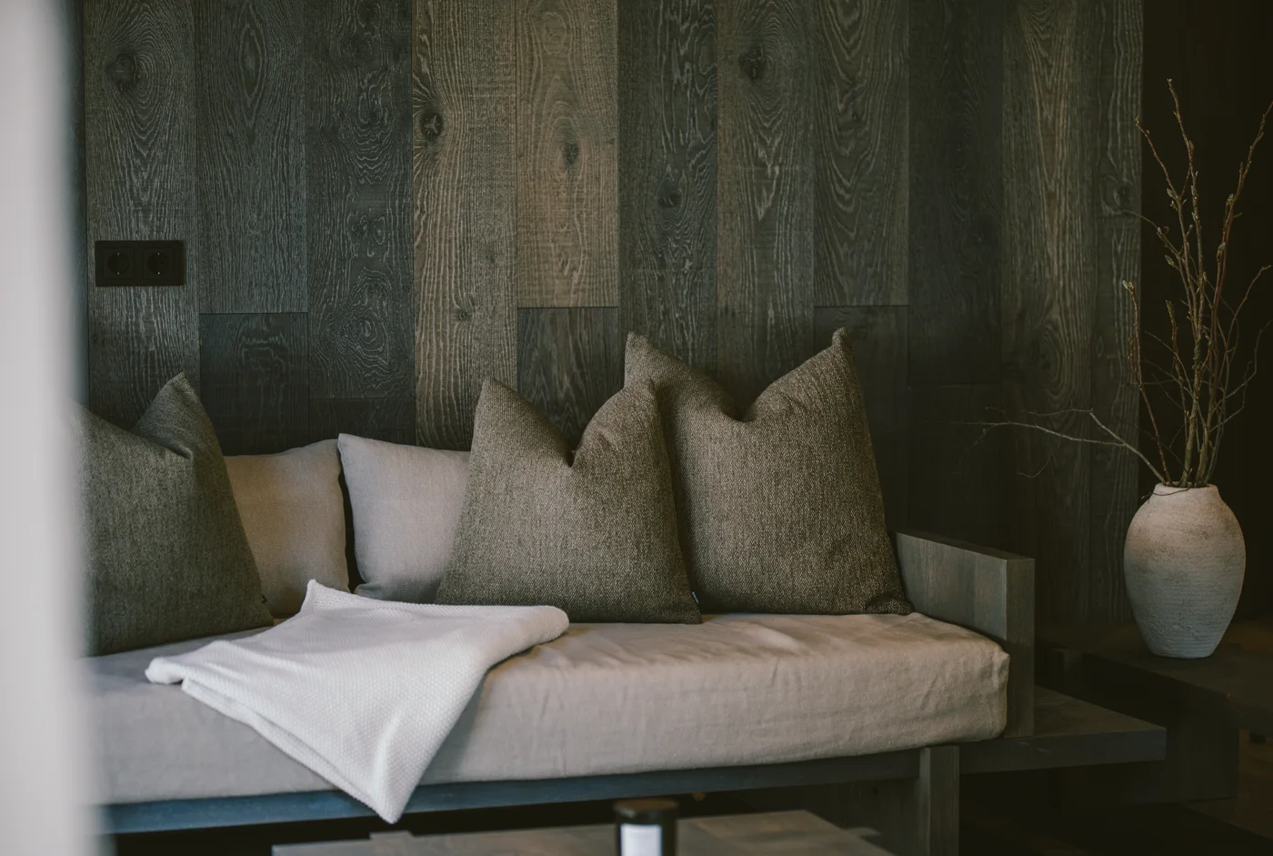 Wohnbereich-Detail einer Birgkar-Lodge – Sofa mit Kissen vor Eichenholzwand