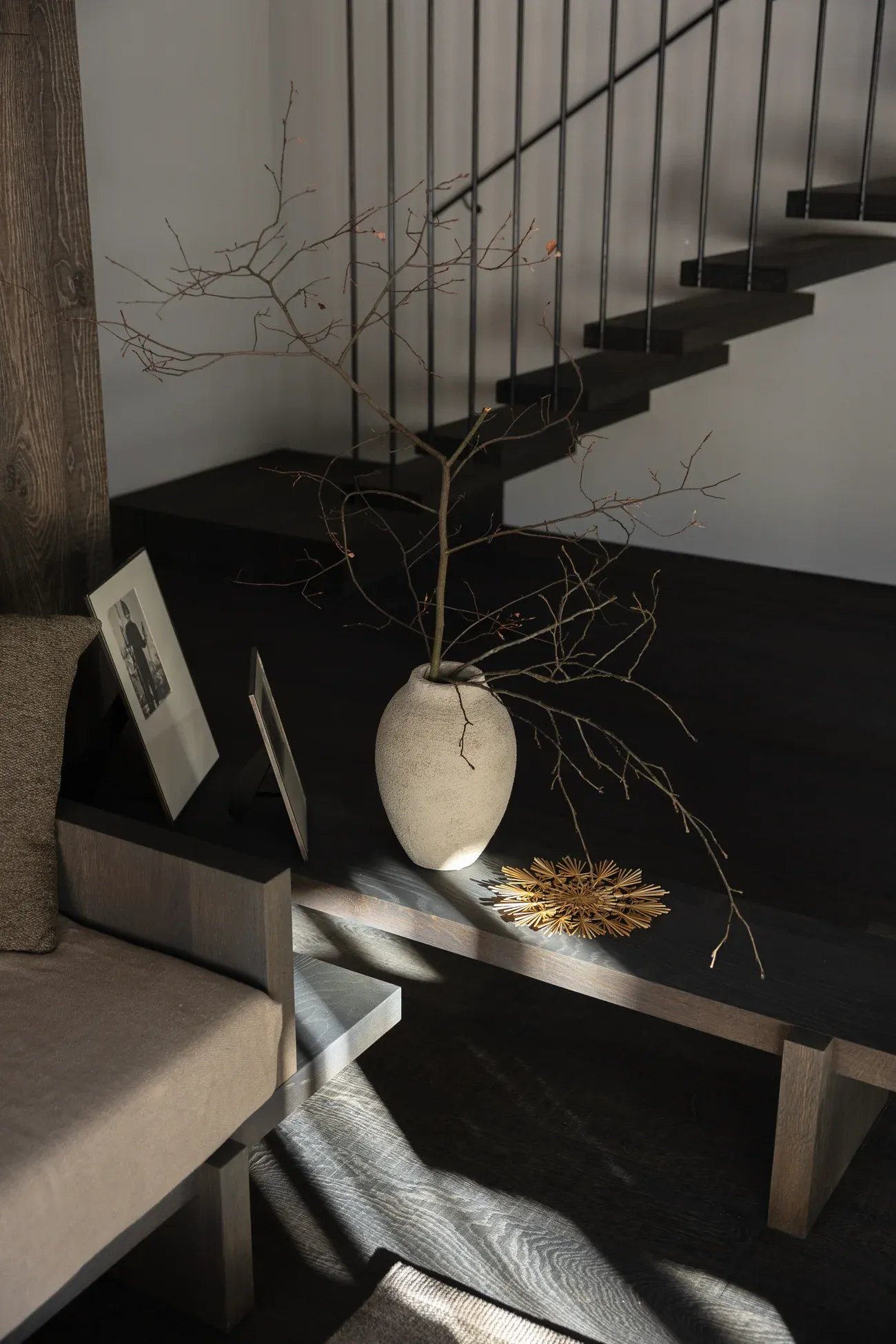 Stilvolles Wohn-Detail einer Birgkar-Lodge – Vase mit Zweigen und gerahmtes Foto in warmem Licht
